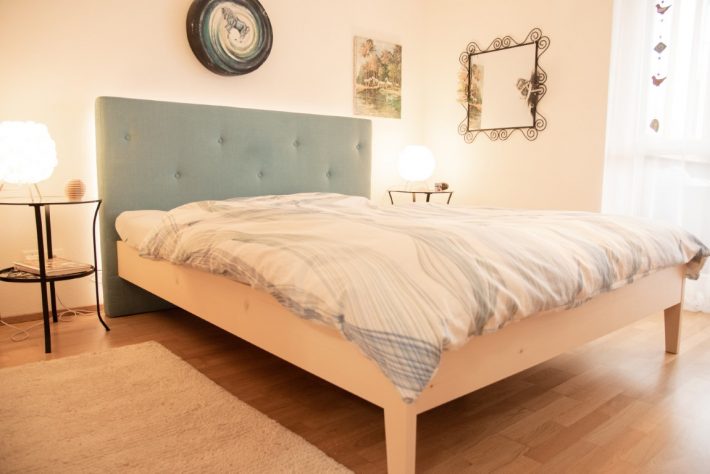 Schlafzimmer mit Bettgestell Fichte mit Kopfteil aus Stoff auf Holzboden mit Hüsler Nest Naturbett Inhalt